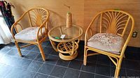Two rattan chairs flanking a rattan side table with glass top