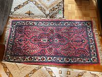 Full view of the Iranian decorative carpet displaying central floral designs and outer border.