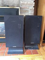 Full view of two Genesis speakers side by side showing fabric covers and bases