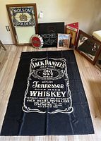 Overview photo showing all items together including Molson Golden stained glass, Michelob Light sign, Coca-Cola bottle cap sign, Jack Daniels tapestry, and framed Coca-Cola sign.