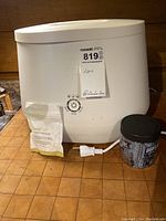 Front view of white Lomi electric composter with power cord, accelerator pouch and additional container.