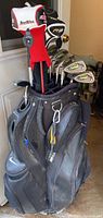 Nike black golf bag filled with left-handed clubs, two headcovers (TaylorMade R9 and Tour Edge) on top