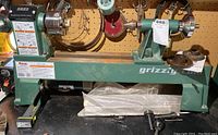 Full front view of green Grizzly lathe on bench