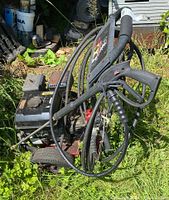 Front angle view of the gas engine and pressure washer gun resting on the ground surrounded by grass.