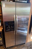 Full front view of stainless steel KitchenAid side by side refrigerator, showing handles and external dispenser panel.