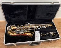 Alto saxophone and accessories seated in open velvet-lined hard case