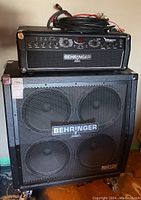 Amplifier head stacked atop speaker cabinet with cables coiled on top