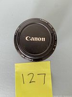 Top view of the Canon EF 50mm f/1.8 II lens with front lens cap on showing the Canon logo and lens specifications.