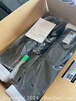 Open box view showing the black soundbar speaker and accompanying accessories sealed in plastic, including power adapter and user manual.