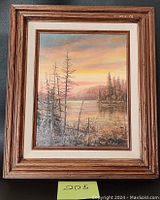 Full view of framed painting showing natural lakeside landscape at sunset with trees, mountains, and water.