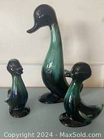 Set of three Blue Mountain Pottery duck and ducklings against a wall.