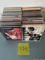 Lot of approximately 40 music CDs seen from top angle showing spines and front covers in two stacks.