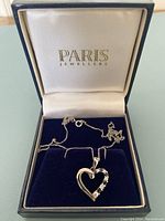 Silver heart pendant necklace in Paris Jewellers branded box with blue interior, showing the pendant and chain coiled inside.
