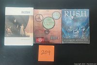 Front covers of three Rush tour concert videos showing the Rush Exit Stage Left DVD, Rush Time Machine 2011 Blu-Ray, and Rush Clockwork Angels Tour DVD in new condition.