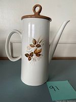 Front view of the Swinnertons coffee pot showcasing the brown lid with loop handle and leaf design decal on white ceramic body.