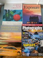 Top-down photo of three Bryan Peterson photography books and one Photography Monthly magazine on tabletop.
