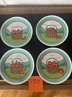 Four ceramic salad/dessert plates with colorful fruit basket designs displayed on a black surface.
