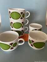 Stacked six vintage coffee cups showing the green and brown design and handles