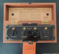 Top view of the opened resistance box showing four numbered dials for resistance settings and internal instruction sheet.