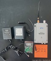 Photo of two AC-DC adapters, a wired earpiece or microphone, a small bag with mounting screws, and a ZTV branded radio TV receiver with antenna on a black surface.