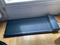 Treadmill unfolded on hardwood floor under window showing top view and belt condition
