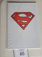Photo of polybagged comic book showing white cover with large red Superman 'S' shield logo.