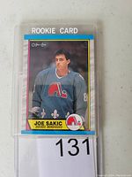 Front of Joe Sakic O-Pee-Chee rookie hockey card showing player portrait in Quebec Nordiques uniform, card #113 with rookie card designation.