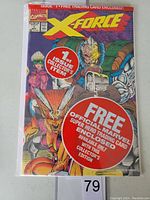 Photo of polybagged X-Force #1 comic book showing cover art, price, issue details, and promotional stickers.