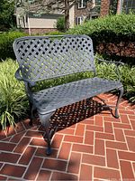 Front left angle view of cast iron loveseat on brick patio in outdoor setting