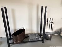 Full view of the fireplace tool set, metal log holder frame, metal boiler, and additional fireplace accessories on the floor.