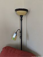 Full view of metal floor lamp showing large upward-facing frosted glass shade and smaller adjustable reading light with frosted glass shade, dark metal frame.