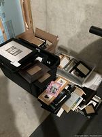 Two plastic tubs and a box filled with assorted picture frames stacked and loose in basement setting