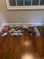 Wide view of multiple Hess toy trucks and vehicles arranged on wooden floor