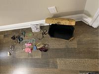 Jewelry box open with various necklaces, bracelets, rings, and sunglasses placed beside it on the floor