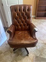 Front view of brown leather tufted back office chair with visible wear on seat