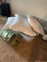 Photo of white quilted pillows on clear plastic container with two ecru pillows leaning against wall