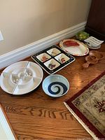 Photo showing multiple serving dishes and bowls including wood guitar dish and various ceramic trays.