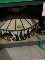 Top angled view of the stained glass hanging lamp showing cream-colored panels and floral border with pink flowers and green leaves.