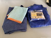Blue Hawk blue tarp in original packaging and moving blankets folded and stacked