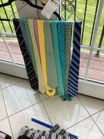 Eight men's ties hanging, showing various colors and patterns.