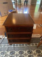 Front view of chest of drawers showing three drawers, ring pull handles, and intact finish with some distressing.