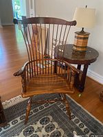 Front-right angled view of wooden spindle back chair showing seat, armrests, and turned legs.