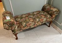 Bench view from an angle showing floral upholstery and curved wooden legs.