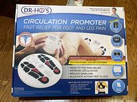 Box front showing Dr. Ho's Circulation Promoter, highlighting fast relief for foot and leg pain and features of the device including foot pads and control unit.