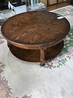 Top-down and angled side views showing wood grain finish and lower shelf of the round coffee table.