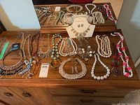 Photo of assorted beaded necklaces, earrings, and bracelets arranged on wooden surface, including Sophia & Kate set on display card