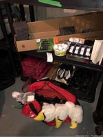 Photo showing golf balls, golf club covers shaped like birds, golf shoes, golf bag on shelf in basement setting