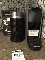 Photo showing the Nespresso Aeroccino3 milk frother and Breville Nespresso coffee maker on a kitchen countertop with mosaic tile backsplash.
