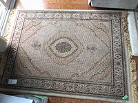 Top-down view of the full Persian style fringed area rug with visible detailed pattern and central medallion, shown next to furniture and hardwood floor.