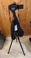 Camera mounted on tripod with carrying case hanging on tripod